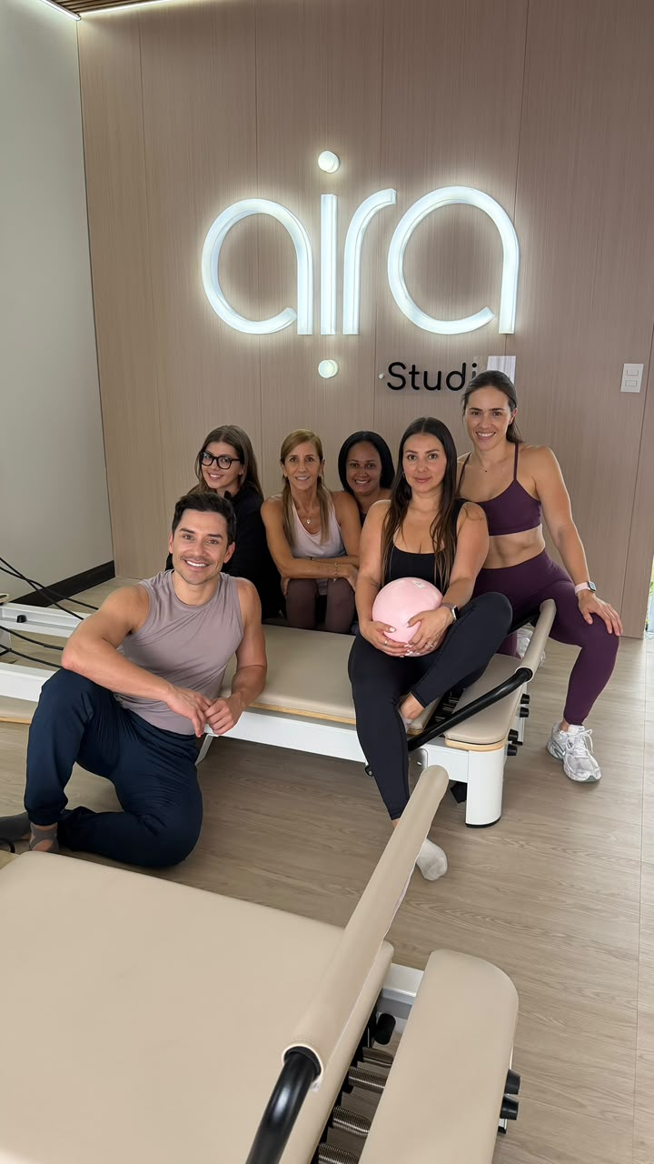 Equipo y alumnos de Aira frente al letrero iluminado del studio